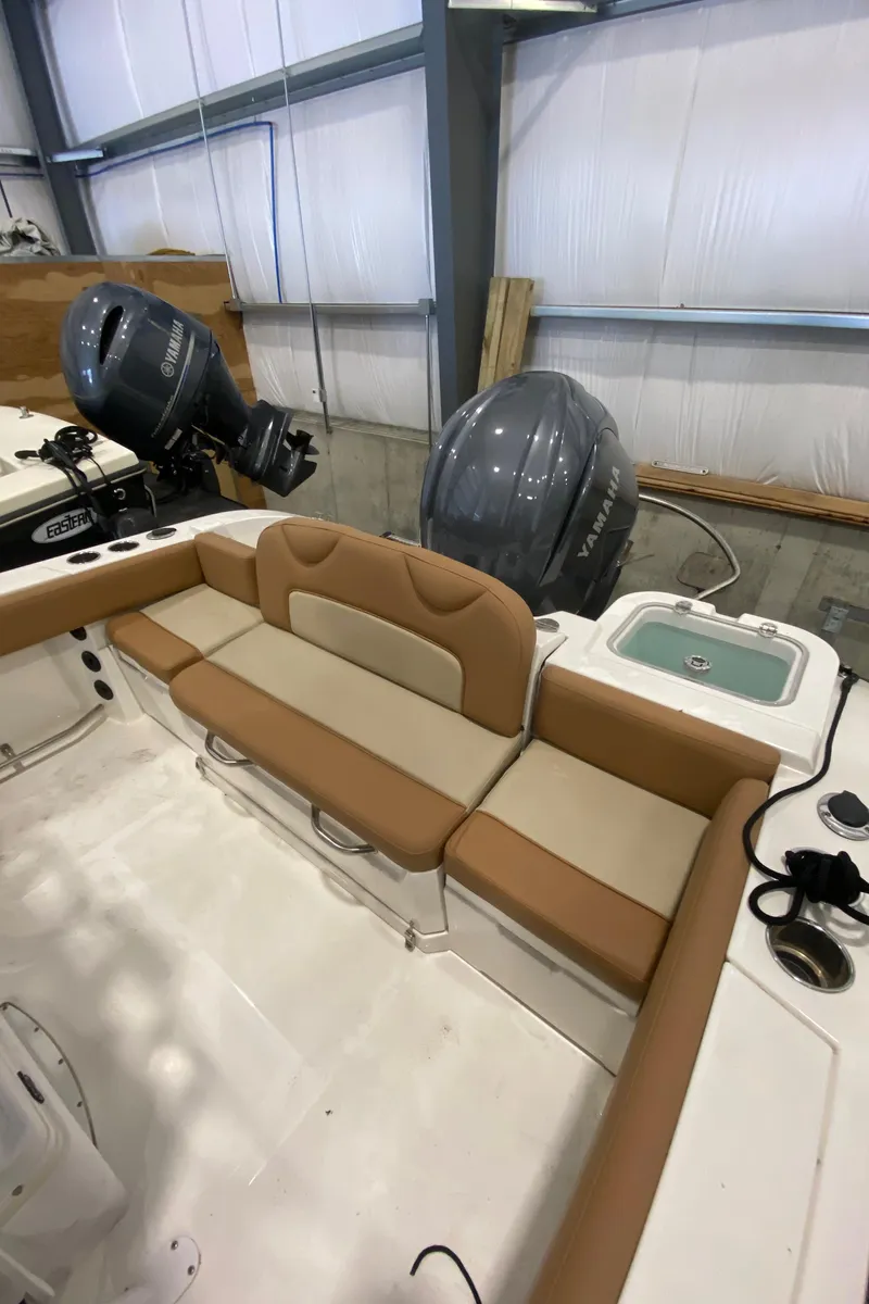 Slide: The Image of 2023 NauticStar 242L Offshore boat interior with tan seating and dual engines. - 5