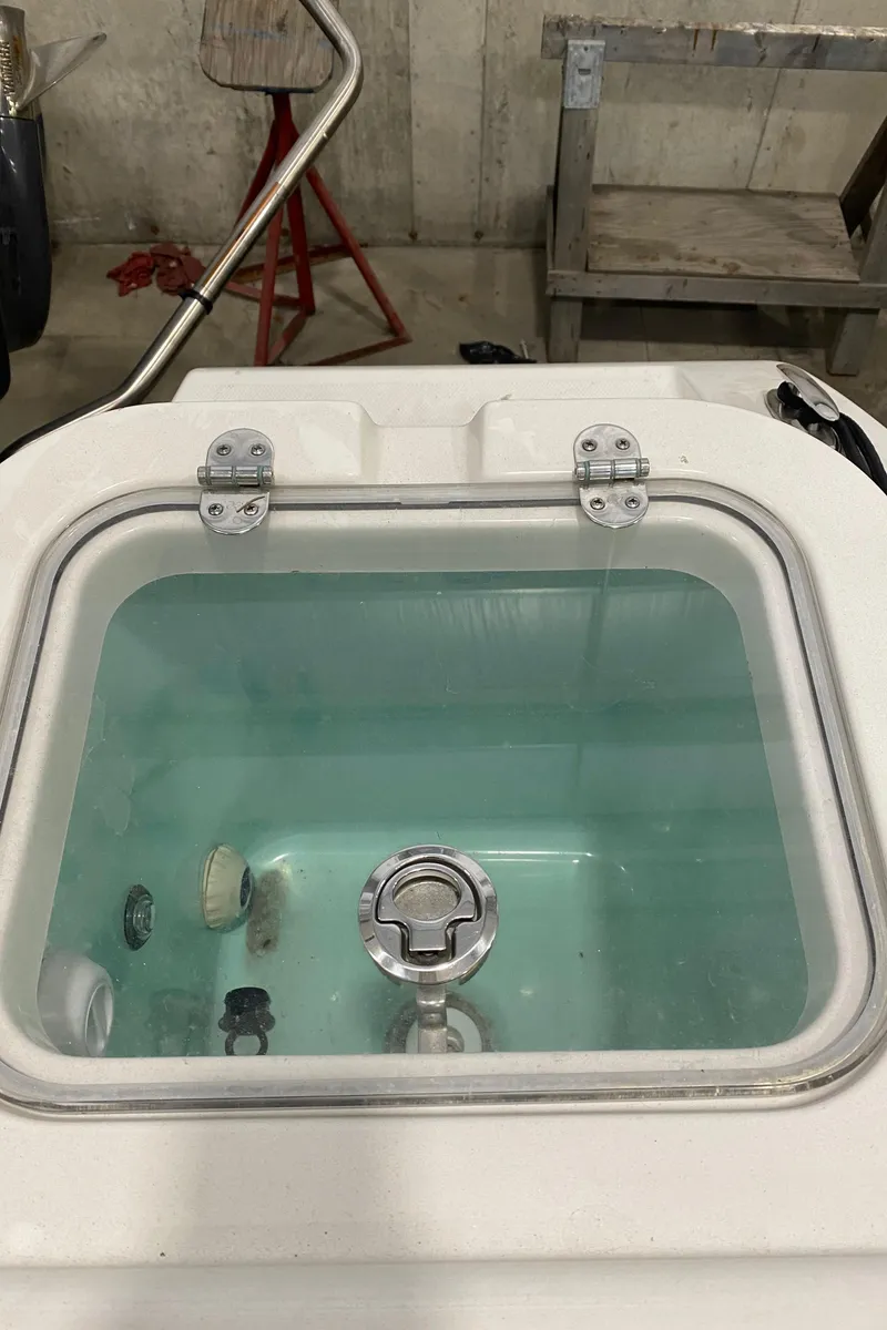 Slide: The Image of Livewell on 2023 NauticStar 242L Offshore boat, featuring clear lid and fittings. - 7