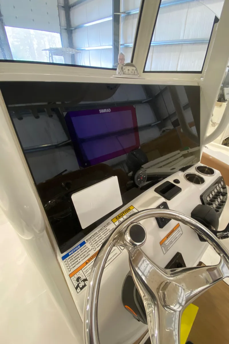 Slide: The Image of 2023 NauticStar 242L Offshore boat dashboard with steering wheel and navigation display. - 9