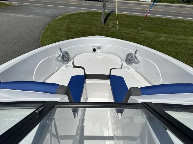 Slide: The Image of 2024 Tahoe 200 S boat interior with blue seating and speakers, parked near a road. - 5