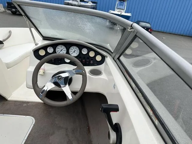 Slide: The Image of 2015 Stingray 191RX boat dashboard with steering wheel and gauges, parked near blue building. - 9