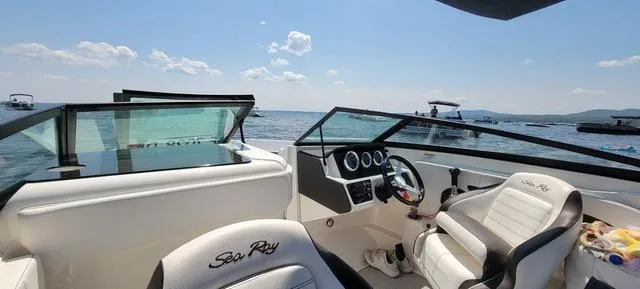 Slide: The Image of 2019 Sea Ray SPX 230 boat interior with white seating, dashboard, and lake view. - 8