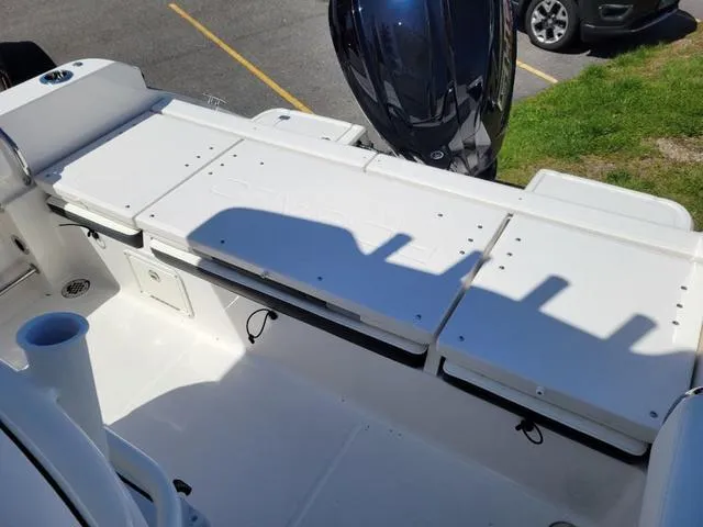 Slide: The Image of 2024 Robalo R232EX boat interior with seating and motor, parked on pavement. - 14