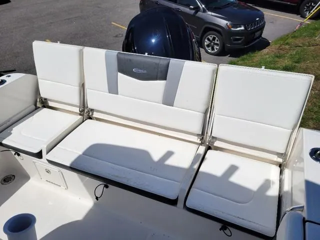 Slide: The Image of 2024 Robalo R232EX boat seating with white cushions and storage compartments. - 16