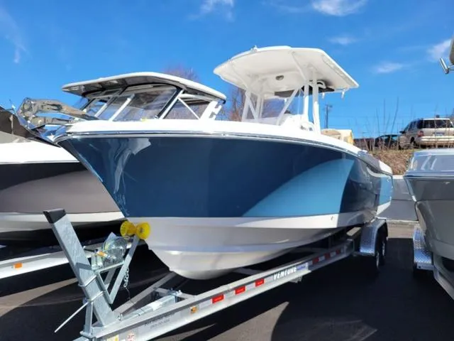 Slide: The Image of 2024 Edgewater 245CC boat on trailer, blue hull, sunny day. - 1