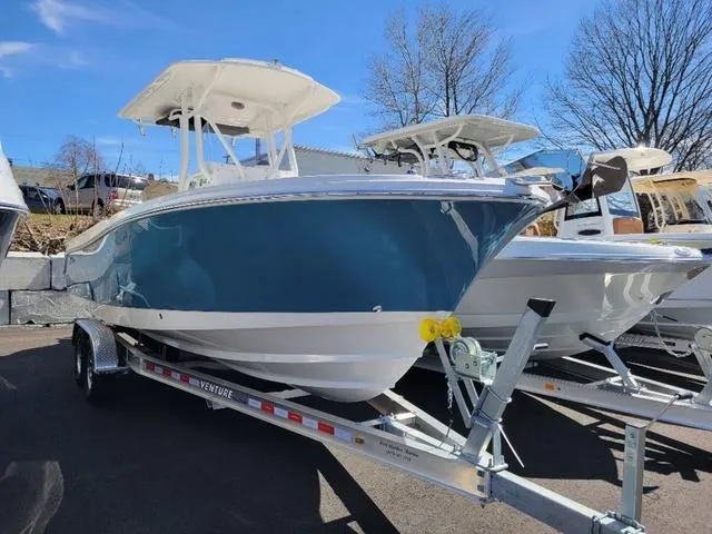Slide: The Image of 2024 Edgewater 245CC boat on trailer, blue hull, sunny day. - 2