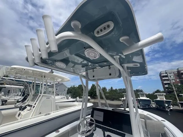 Slide: The Image of 2025 Sea Hunt Ultra 219 boat with T-top and rod holders, docked under a cloudy sky. - 18