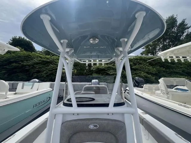 Slide: The Image of 2025 Sea Hunt Ultra 219 boat with T-top, docked among other boats. - 8