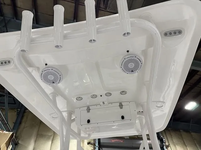 Slide: The Image of 2025 Sea Hunt Ultra 229 boat roof with speakers and rod holders in a warehouse. - 11