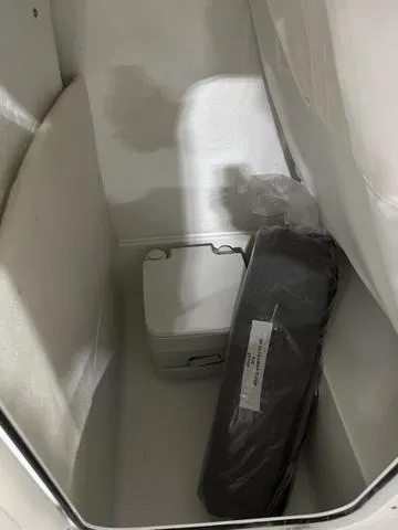 Slide: The Image of Storage compartment in a 2025 Sea Hunt Ultra 229 boat, featuring a white container and packaged item. - 15