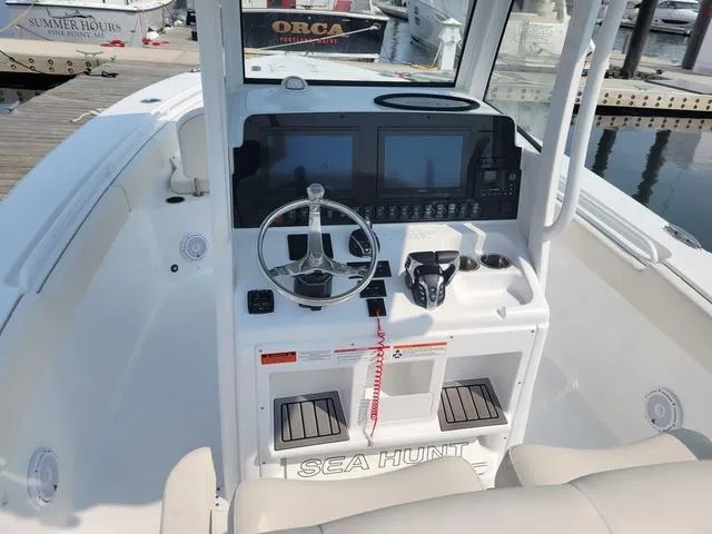 Slide: The Image of 2024 Sea Hunt Gamefish 27 boat dashboard with dual screens and steering wheel. - 7