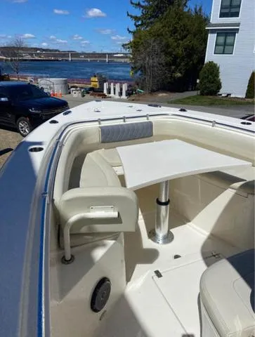 Slide: The Image of 2019 Cobia 301CC boat with seating and table, docked near a waterfront view. - 10