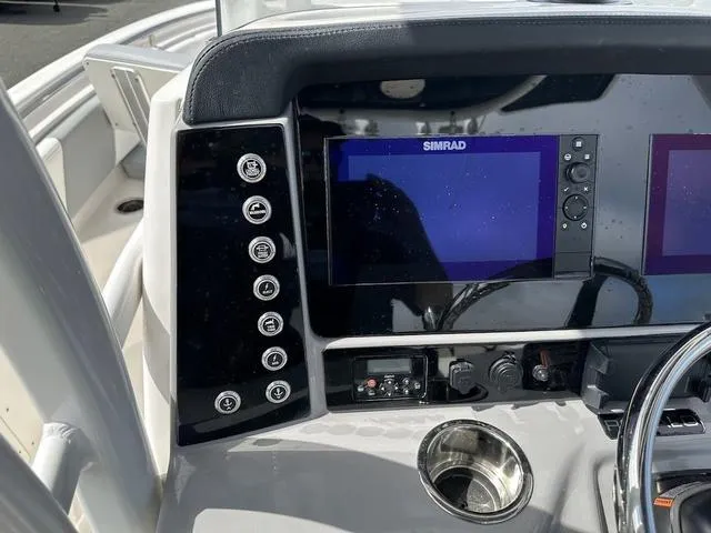 Slide: The Image of 2022 Robalo R242 boat dashboard with Simrad displays and control panel. - 10