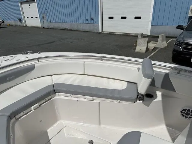 Slide: The Image of 2022 Robalo R242 boat interior with white and gray seating, docked near blue warehouse. - 20