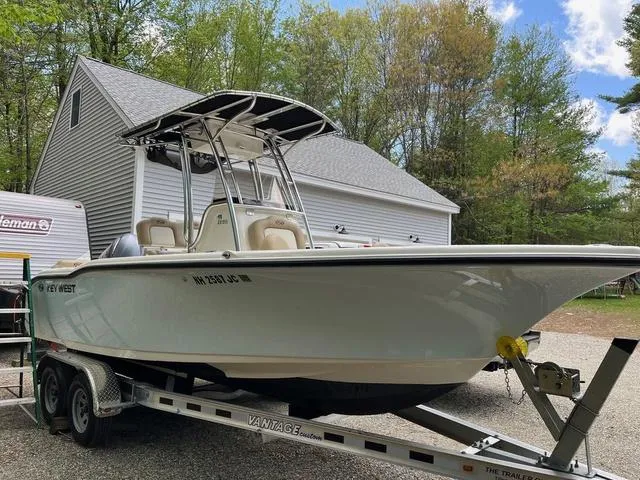 Slide: The Image of 2020 Key West 219fs boat on trailer, parked near a garage in a wooded area. - 2