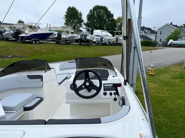 Slide: The Image of 2023 Bayliner Element M17 boat interior with steering wheel, parked outdoors. - 4