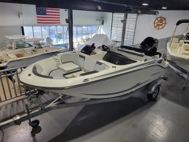 Slide: The Image of 2023 Bayliner Element M17 boat displayed indoors with American flag backdrop. - 6