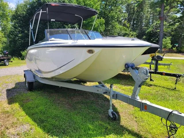 Slide: The Image of 2024 Bayliner M19 boat on trailer, parked on grass, with canopy, in a wooded area. - 3