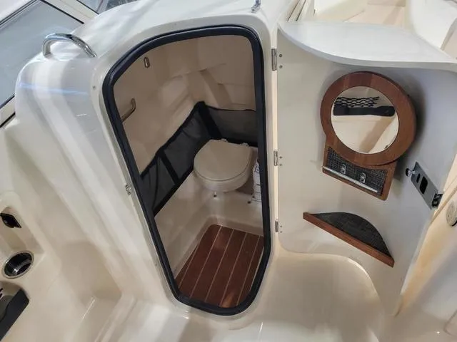 Slide: The Image of 2024 Grady-White Freedom 255 boat interior with compact bathroom and wooden accents. - 11