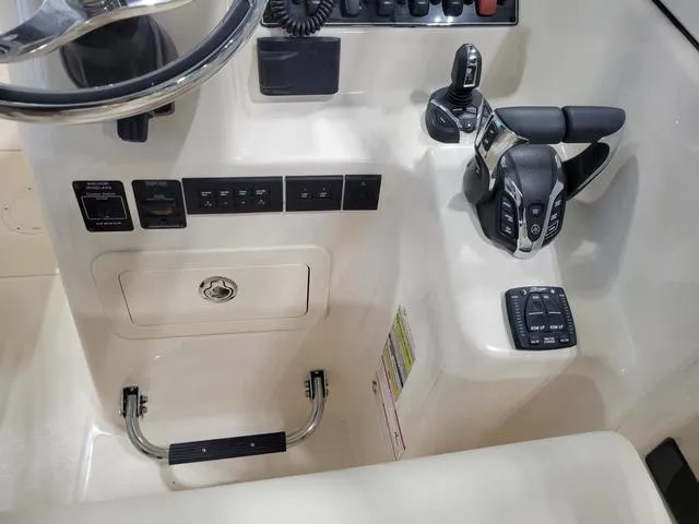Slide: The Image of 2024 Grady-White Freedom 255 boat controls and dashboard, featuring modern steering and throttle systems. - 13