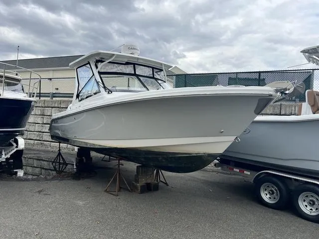 Slide: The Image of 2022 Edgewater 262CX boat on trailer, parked outdoors under cloudy sky. - 1