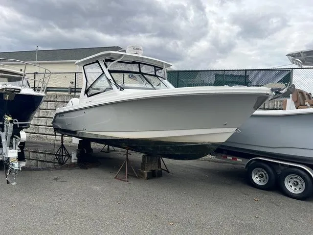 Slide: The Image of 2022 Edgewater 262CX boat on trailer, parked outdoors under cloudy skies. - 15