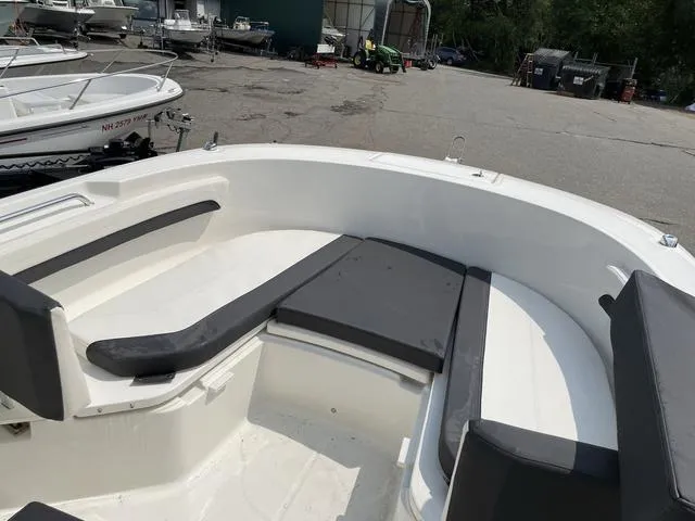 Slide: The Image of 2023 Trophy T 24 CC boat interior with cushioned seating in a marina setting. - 6