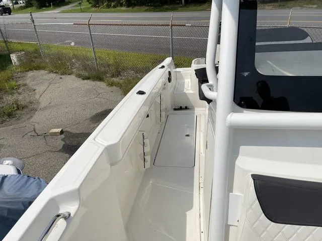 Slide: The Image of 2023 Trophy T 24 CC boat, white deck, parked near a fence. - 9