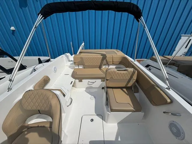 Slide: The Image of 2024 Bayliner VR6 boat interior with tan seating and blue backdrop. - 7