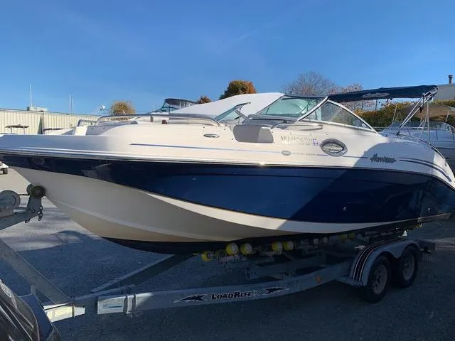 Slide: The Image of 2006 Hurricane 25' DC boat on trailer, blue and white design, parked outdoors. - 2