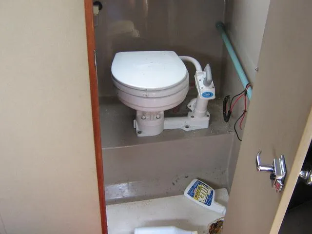 Slide: The Image of 1983 Bayliner 2850 Contessa boat bathroom with toilet and cleaning supplies. - 10