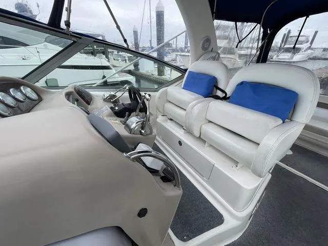 Slide: The Image of 2003 Sea Ray 340 Sundancer helm with white seats and blue cushions. - 12