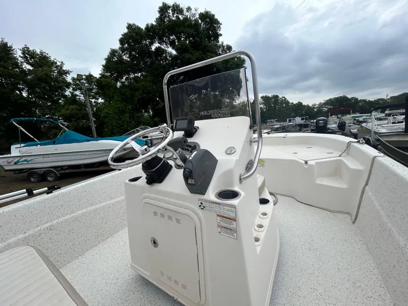 Slide: The Image of 2018 Carolina Skiff 198 DLV boat console with steering wheel and controls, docked outdoors. - 10