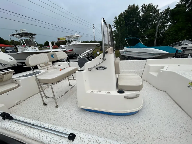 Slide: The Image of 2018 Carolina Skiff 198 DLV boat with seating and console, displayed outdoors. - 12