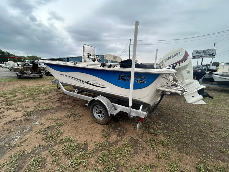 Slide: The Image of 2018 Carolina Skiff 198 DLV boat on trailer with Evinrude motor, parked outdoors. - 3
