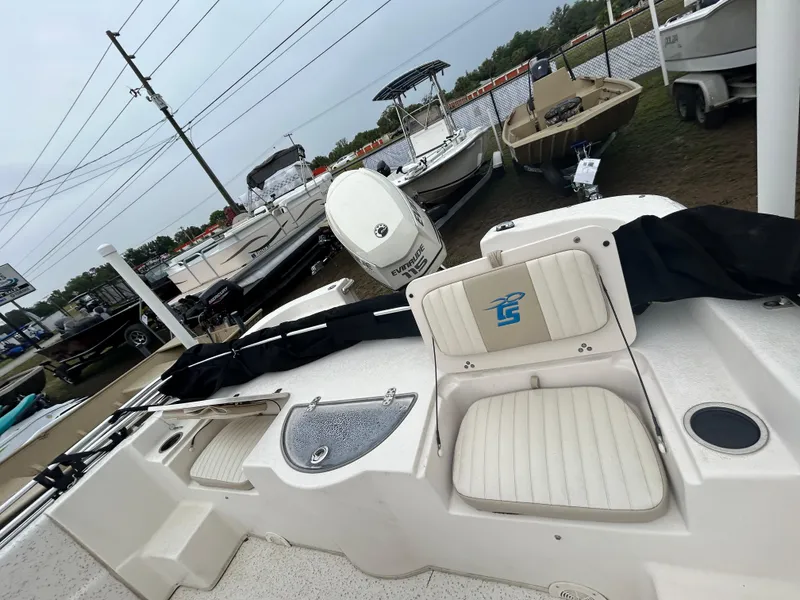 Slide: The Image of 2018 Carolina Skiff 198 DLV boat interior with seating and motor, displayed outdoors. - 5