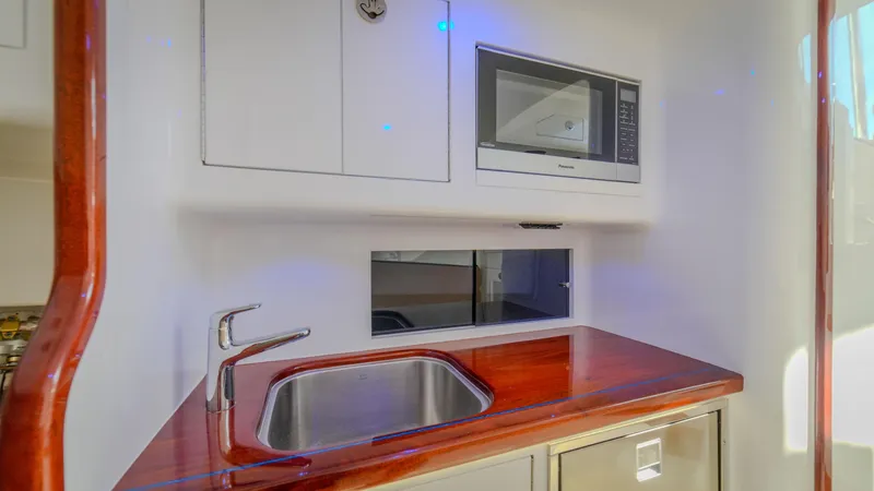 Slide: The Image of 2024 Maverick Yachts Costa Rica 36 Walkaround kitchen with sink, microwave, and wooden countertop. - 24
