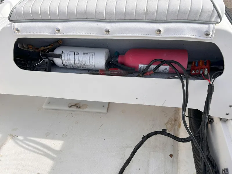 Slide: The Image of Storage compartment in a 1998 Boston Whaler 13 Sport boat with fire extinguishers and wiring. - 17