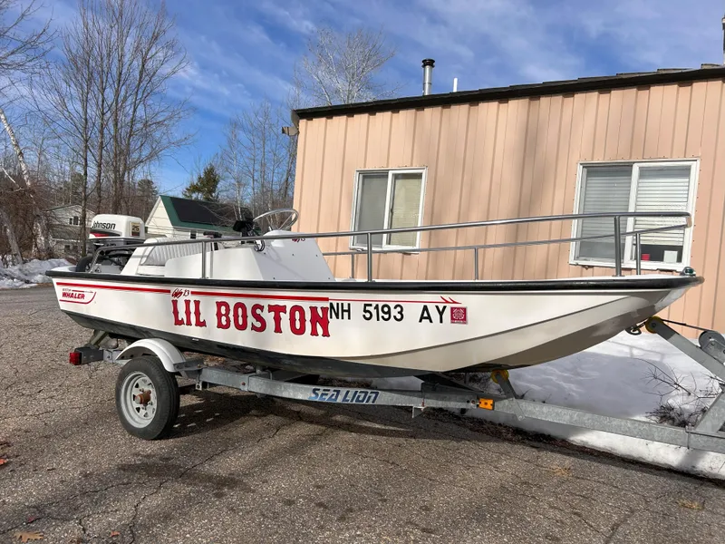 Slide: The Image of 1998 Boston Whaler 13 Sport boat on trailer, labeled "Lil Boston," parked outdoors. - 2