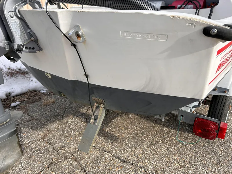 Slide: The Image of 1998 Boston Whaler 13 Sport boat stern with motor and trailer on pavement. - 21