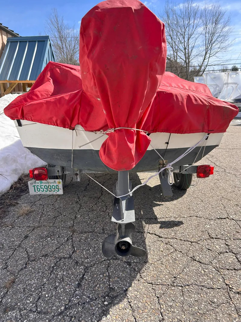 Slide: The Image of 1998 Boston Whaler 13 Sport boat with red cover on a trailer, parked outdoors. - 27