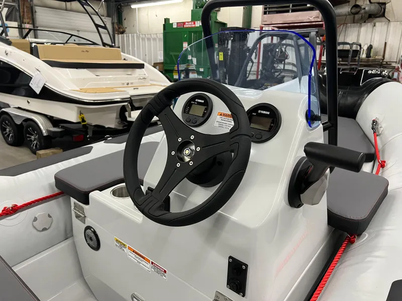 Slide: The Image of 2023 Zodiac Open 4.2 boat dashboard with steering wheel and controls in a showroom. - 6