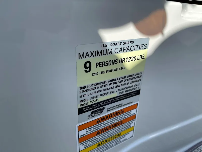 Slide: The Image of U.S. Coast Guard capacity label on 2020 Crownline 205 SS boat, max 9 persons or 1220 lbs. - 16