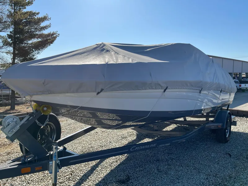 Slide: The Image of 2020 Crownline 205 SS boat covered on a trailer, parked outdoors. - 21