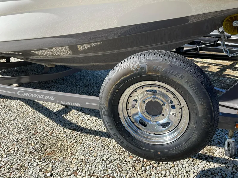 Slide: The Image of 2020 Crownline 205 SS boat trailer with tire on gravel surface. - 22