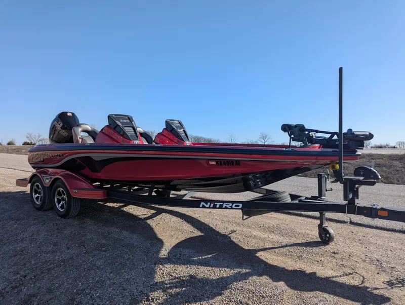 Slide: The Image of 2023 Nitro Z20 boat on trailer, red and black design, parked on gravel. - 10