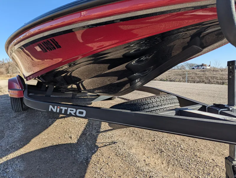 Slide: The Image of 2023 Nitro Z20 boat on trailer, red hull, parked on gravel. - 11