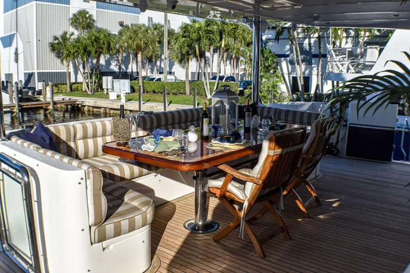 Slide: The Image of Outdoor dining area on 2006 Johnson Country Kitchen yacht, featuring striped seating and wooden table. - 4