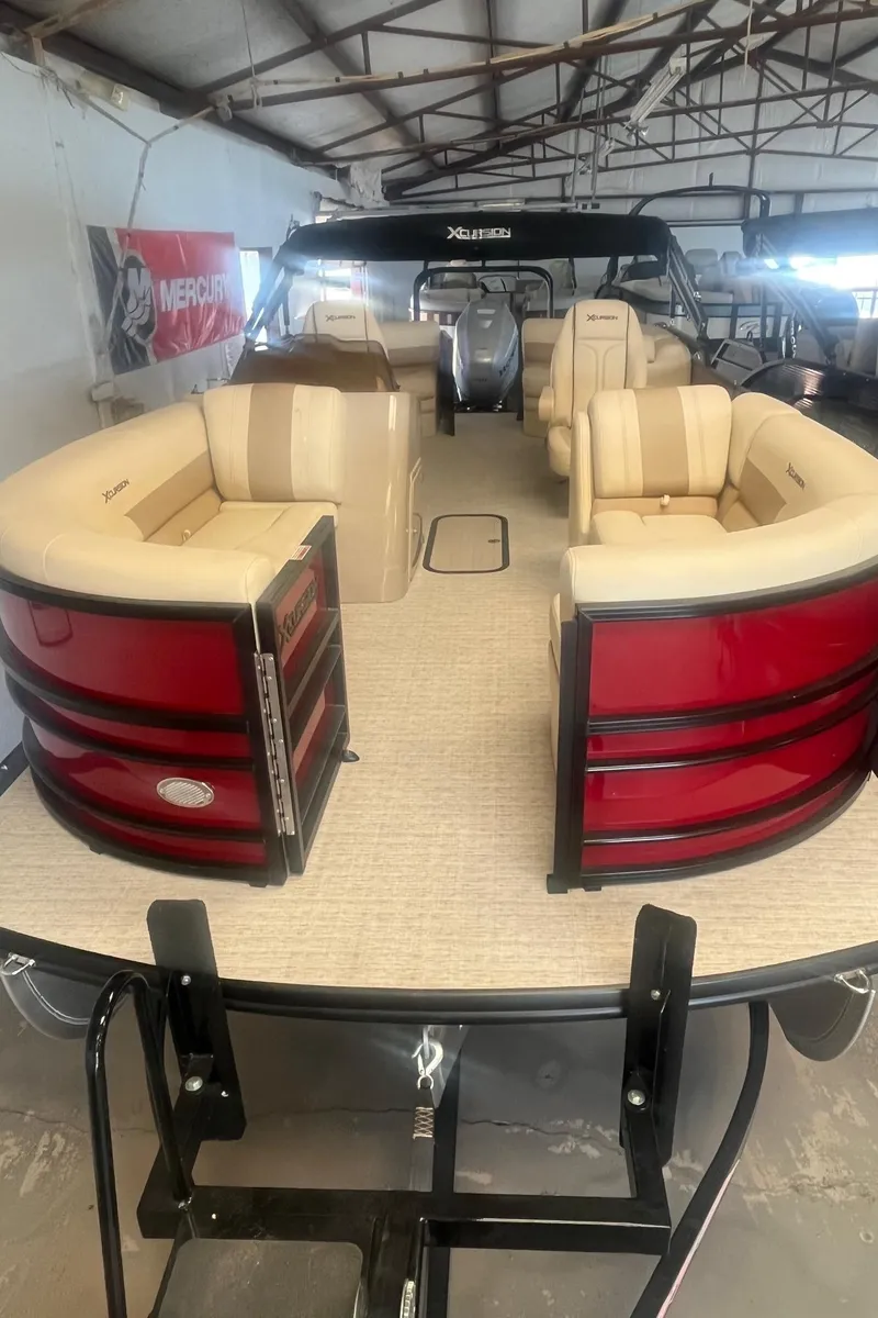 Slide: The Image of 2022 Xcursion 223 RFX pontoon boat with beige seating and red accents in a warehouse. - 3