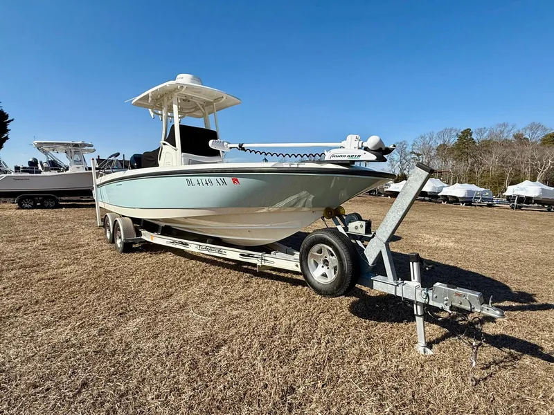 Slide: The Image of 2016 Boston Whaler 240 Dauntless boat on trailer, parked on grass under clear blue sky. - 2